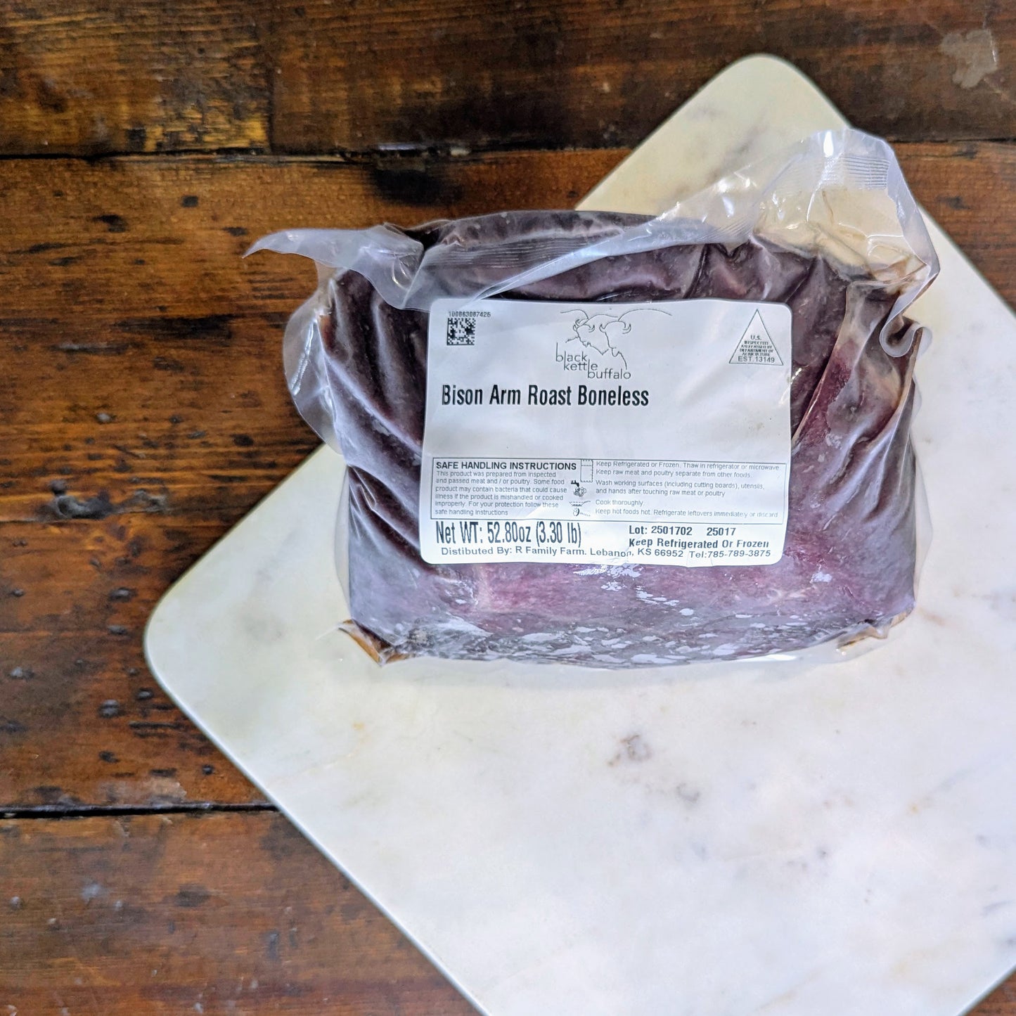 Packaged bison arm roast on a wooden surface with a label