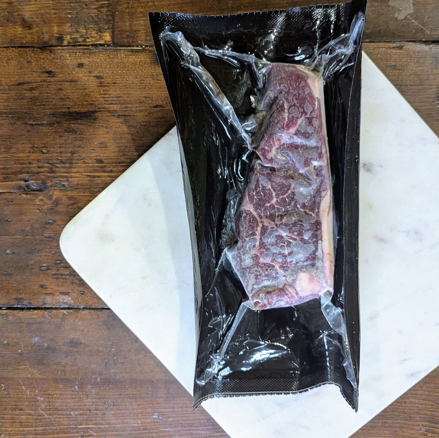 Vacuum-sealed package of raw meat on a wooden surface