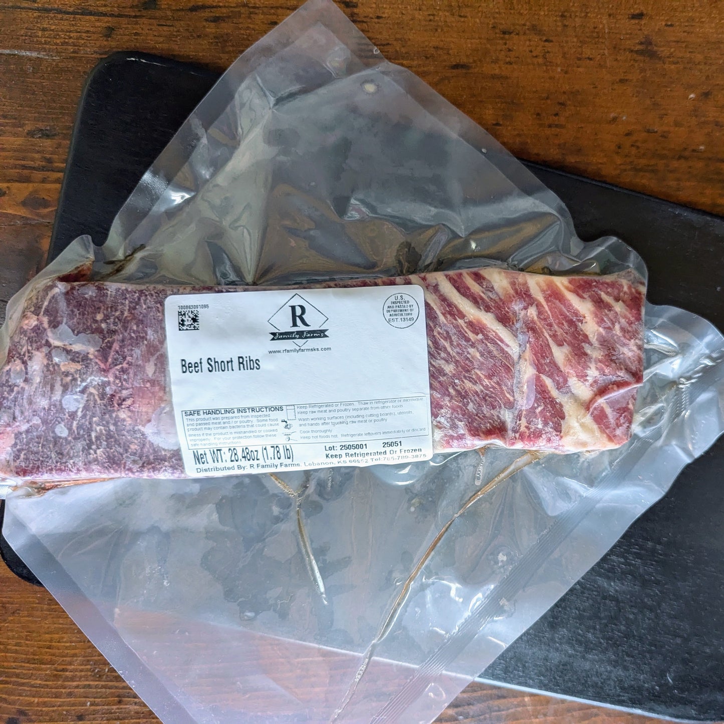 Packaged beef short ribs with a label on a wooden surface
