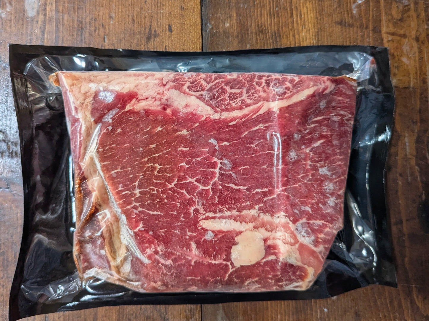 Raw steak in a vacuum-sealed package on a wooden surface