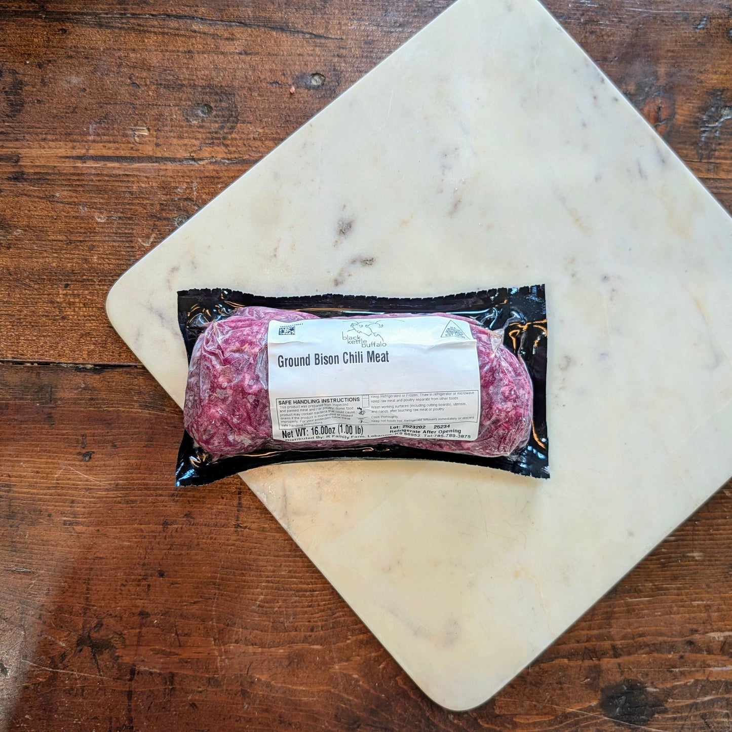 Packaged ground beef on a marble cutting board with a wooden background