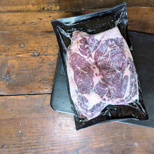Raw steak in a vacuum-sealed package on a wooden surface
