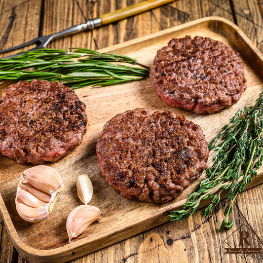 Ground American Bison Patties on a wooden cutting board with fresh herbs.
