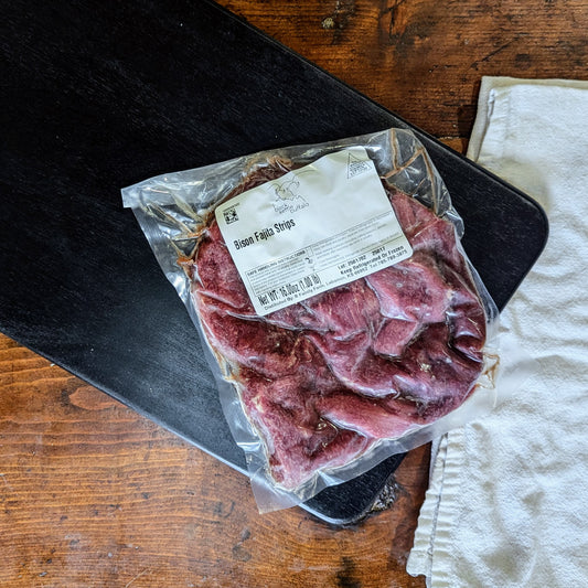 Packaged bison strips with a label on a wooden surface