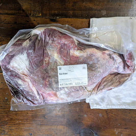 Rawbisonbrisket in a with a label on a wooden surface