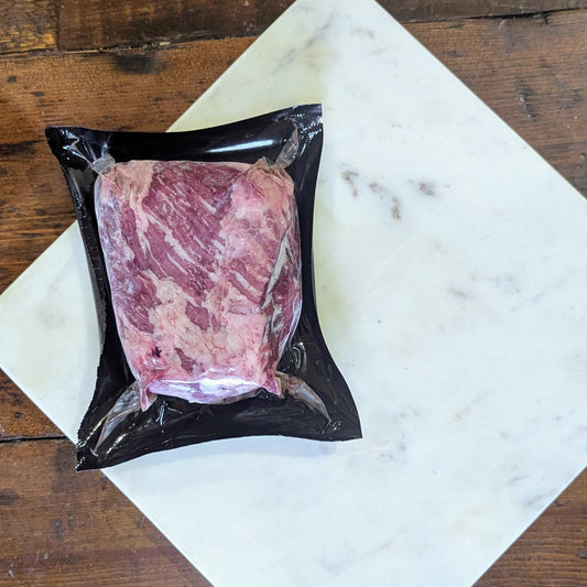Packaged raw meat on a marble slab with a wooden background