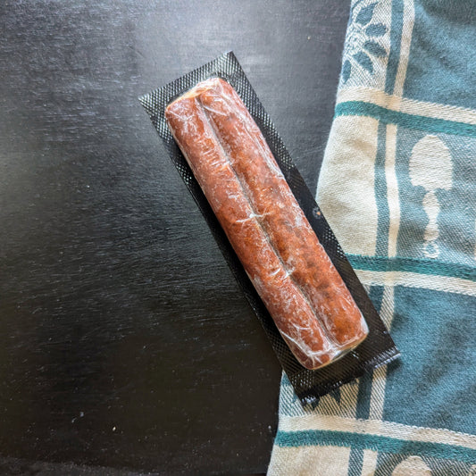 Packaged sausage on a black surface with a patterned cloth underneath