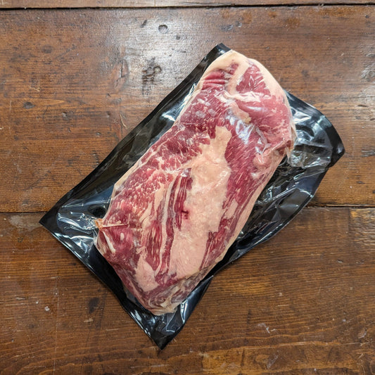 Raw steak on a black plastic wrap on a wooden surface