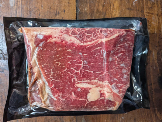 Raw steak in a vacuum-sealed package on a wooden surface