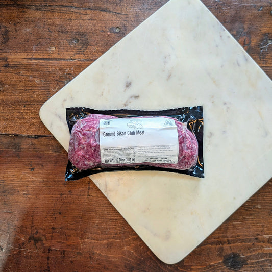 Packaged ground beef on a marble cutting board with a wooden background